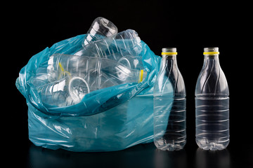 Empty plastic bottles in a garbage bag. Household waste collected in a blue bag.