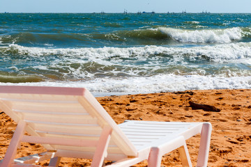 White lounge chair standing on a sandy beach by the sea