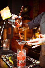 Fototapeta na wymiar Expert barman is making cocktail at night club