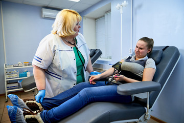 Obraz premium Experienced doctor fat woman taking care of a sick girl on the couch in the medical office