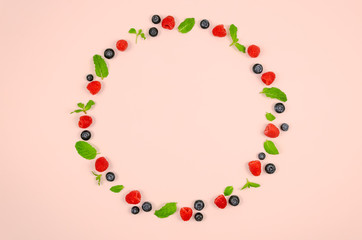 Fresh blueberries, raspberries and mint leaf on top view with pastel pink color background for healthy food concept.