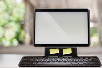 Fototapeta premium A computer with a touchscreen and wireless keyboard on a white desk with a window view in the background.
