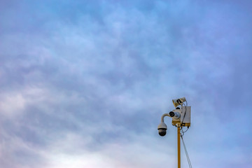 Outdoor security camera isolated against a cloudy blue sky background