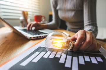 light bulb with business hand working with tablet, laptop computer and creative business strategy in morning light