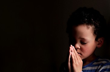 little boy praying to God stock image with hands held together with closed eyes stock photo