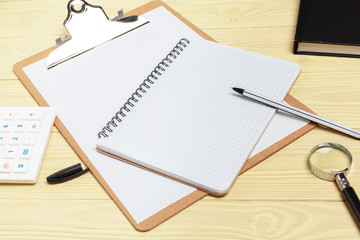 Magnifying glass and notebook on wooden table