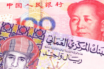 A multicolored one rial note from Oman, close up in macro with a red, Chinese one hundred yuan renminbi bill