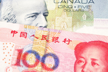 A close up macro shot of a blue five Canadian dollar bill with a one hundred yuan Chinese note 