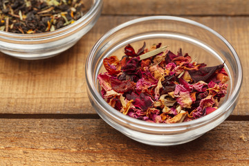 Aromatic dry tea in bowls on wooden background