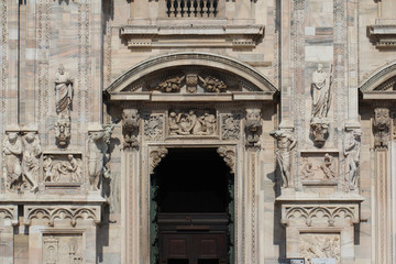 Obraz premium The main gate of Duomo milano, The entry door of Famous white Architectural cathedral church under blue sky at Milan, The largest church in Italy, travel destination backgrounds