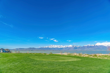 Lush grassy terrain with view of a calm lake and towering snow topped mountain
