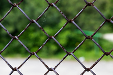 Fototapeta premium Rows of wire mesh and rusty metal pillar of fence. Wire mesh grid texture. Grunge backdrop. Rustic patterned textures.