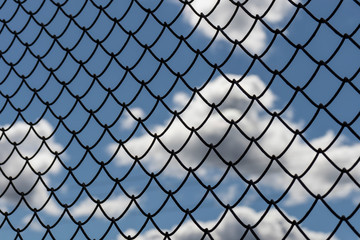 Fototapeta premium Iron fence on a blue sky with clouds.