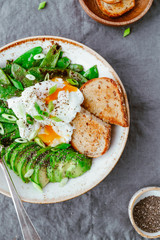 Top view of healthy breakfast or lunch. Fried snow peas, avocado, poached eggs are sprinkled chia seeds with toasts.