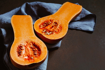 View on raw halves of butternut squash on a kitchen table. Seasonal vegetable food, still life.