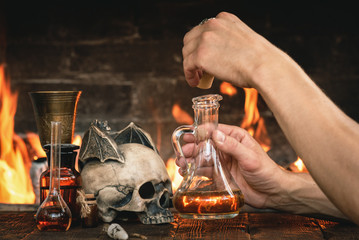 Alchemist or witch doctor or wizard is working at his magic table and producing a magic potion.