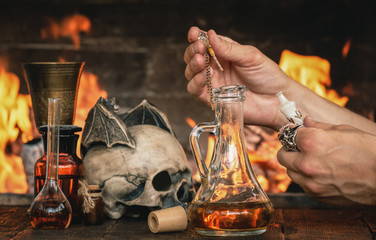 Alchemist or witch doctor or wizard is working at his magic table and producing a magic potion.