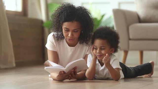 Loving african mother reading book to smart cute kid son