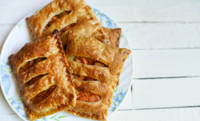 Puff pastry apple pastry turnovers for dessert on a white wooden table with copy space