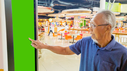 Elderly man using a self-service kiosk in the mall