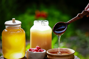 fresh sweet honey dripping in a wooden spoon in a ceramic bowl