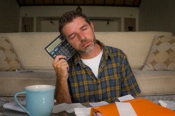 frustrated man at home living room couch doing domestic accounting overwhelmed and worried suffering financial problem going over taxes and payments paperwork