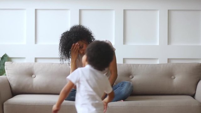 Upset african single mother feeling stressed about active noisy children
