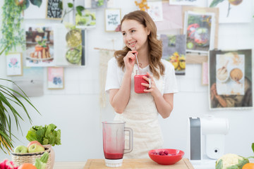 A beautiful girl drinks a freshly made smoothie from berries. The concept of a healthy diet, healthy lifestyle.