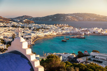 Blick auf den alten Hafen und die Stadt von Mykonos, Kykladen, Griechenland, mit blauer Kirche und türkisem meer bei Sonnenuntergang - obrazy, fototapety, plakaty