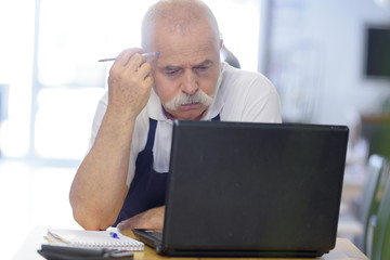 senior man sighing as he uses laptop
