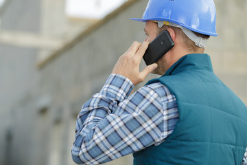 architect supervising a construction using cell phone outdoors