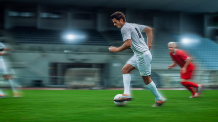 Blurred Motion Shot of Professional Soccer Player Leads with a Ball. Two Professional Football Teams Playing On a Stadium.