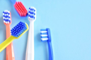 Colorful toothbrushes with selective focus on blurred blue background. Dental tools for daily teeth protection. Multicolored plastic toothbrush with bright bristles with soft focus. Oral hygiene 