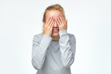 Young woman covering her eyes with her hands expecting to see a surprise on your birthday. Positive facial emotion studio shot