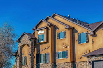 Home with concrete and stone brick wall against leafless tree and clear blue sky