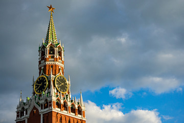 Ruby ​​star and  clock on Spasskaya Tower of Moscow Kremlin on Red Square is historic landmark. Huge clock against blue sky with dark clouds. There is place for text.