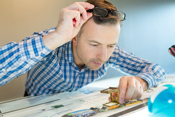 worker uses a magnifying glass at printer