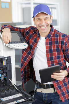 serviceman with tablet carrying out photocopier maintenance