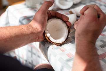 Man cut fresh coconut into pieces, process close up. Exotic food