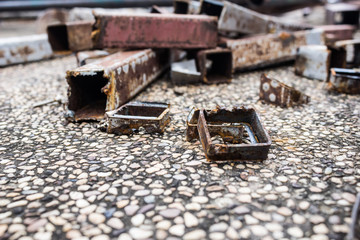 Steel rods and rusted scrap steel are placed on the floor and close-up photography