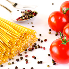 Spaghetti lie on a white background, along with cherry tomatoes