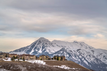 Homes with view of towering snow peaked mountain and overcast sky in winter