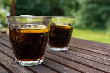 two glasses of cola with slice of lemon. Wooden table.