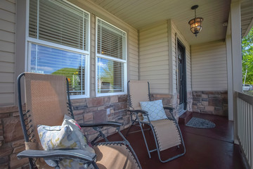 Relaxing chairs with pillows on the porch of a home wood and stone exterior wall