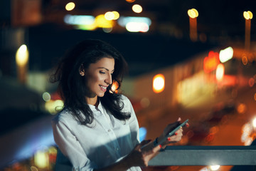 Woman over night cityscape holding a digital tablet texting