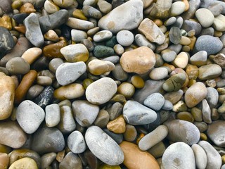 Multi coloured pebbles and stones on beach pattern and texture
