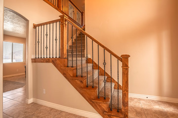 Carpeted stairs with wood handrail and metal railing inside an empty new home