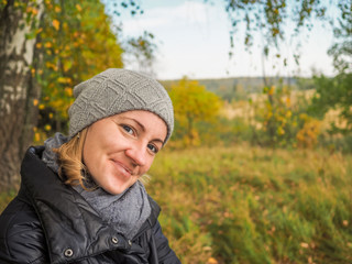 Portrait of a carefree smiling girl on the background of a fading autumn forest. Cloudy October day.