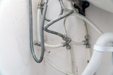 Old dirty sink with wrong connection of pipes and other plumbing. Selective focus