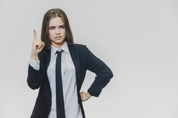 Young pretty businesswoman is pointing her finger up with an aversion face.